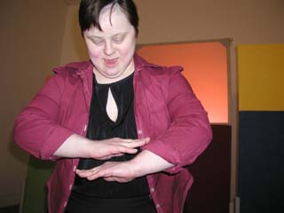Photo of Laura in front of coloured fabric screens dancing with her hands